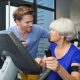 Older woman patient talking with a chiropractic and physical therapist as she is on an exercise machine